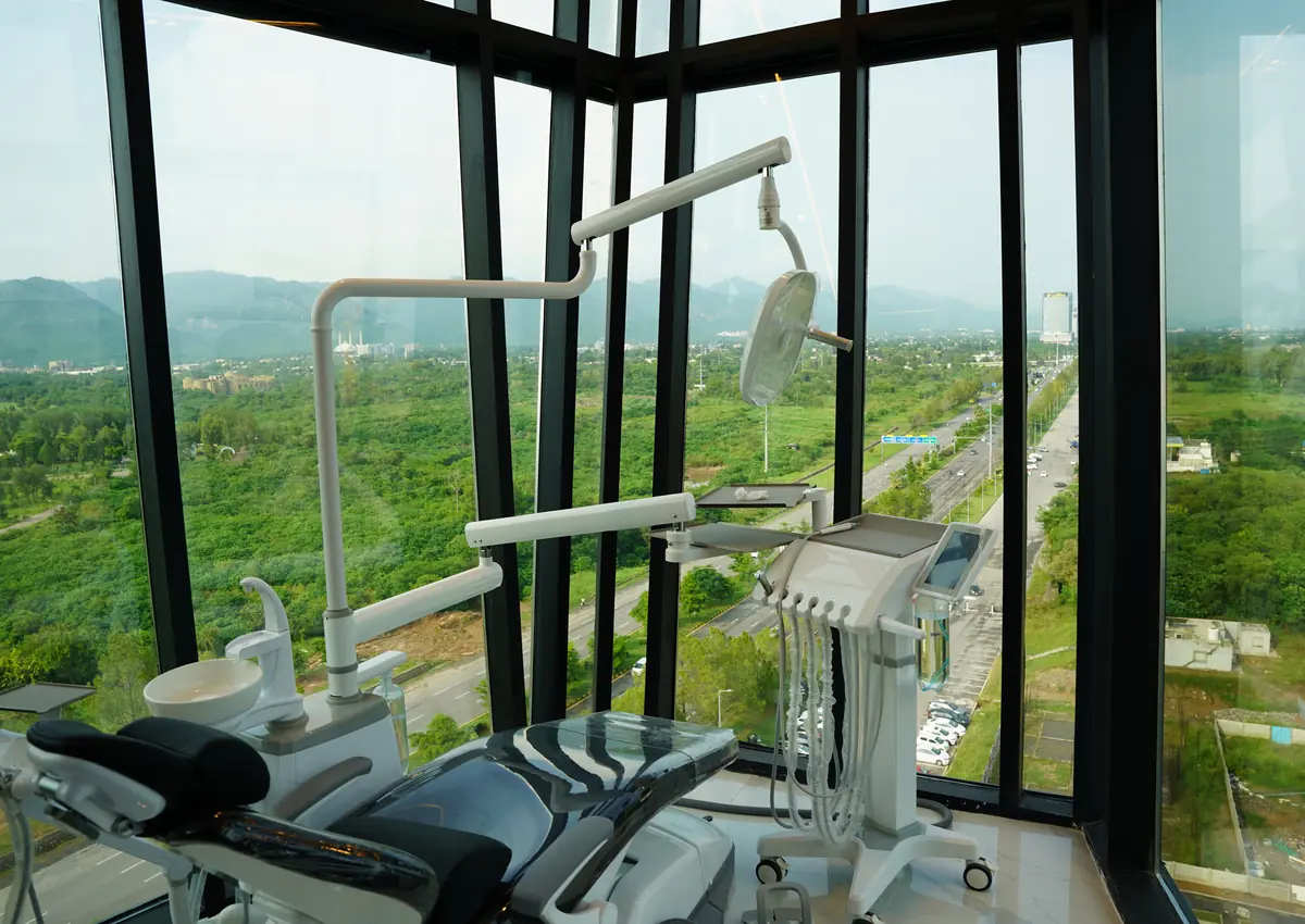 Dental chair and delivery unit beside floor-to-ceiling windows at Tooth Crew Clinic, New Blue Area